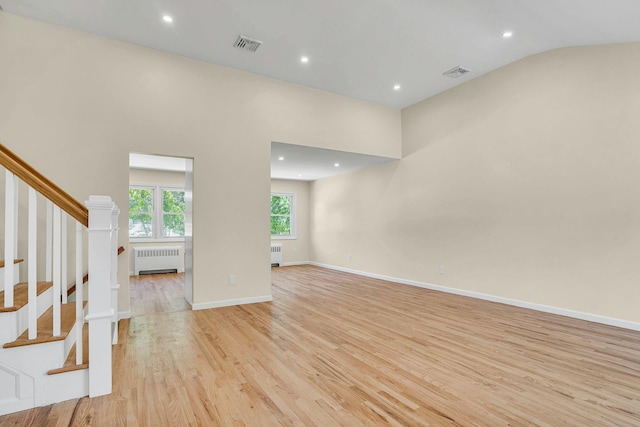 unfurnished living room featuring radiator heating unit, light wood-style flooring, stairway, recessed lighting, and baseboards