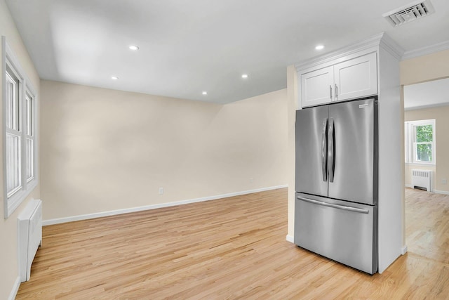 kitchen featuring freestanding refrigerator, radiator heating unit, light wood-style flooring, white cabinets, and baseboards