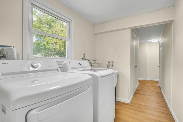 laundry area featuring washing machine and dryer, light wood-style floors, and baseboards