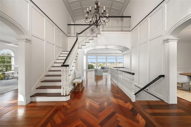 52 Carriglea Dr, Call Listing Agent, CT 06878 - staircase with arched walkways, decorative columns, a decorative wall, high vaulted ceiling, and a chandelier