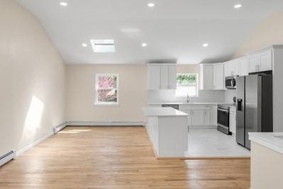 8 Hilltop Ave, West Babylon, NY 11704 - kitchen with appliances with stainless steel finishes, vaulted ceiling, light wood-style floors, light countertops, and white cabinetry