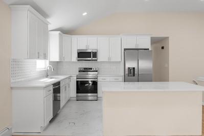 8 Hilltop Ave, West Babylon, NY 11704 - kitchen with stainless steel appliances, decorative backsplash, white cabinetry, lofted ceiling, and light countertops