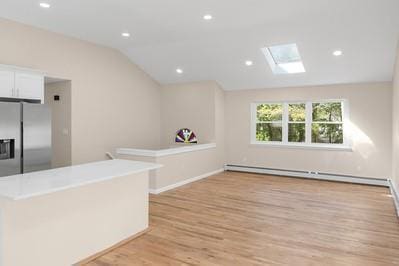 8 Hilltop Ave, West Babylon, NY 11704 - bar area with stainless steel fridge with ice dispenser, lofted ceiling, a skylight, light wood-style floors, and a baseboard radiator