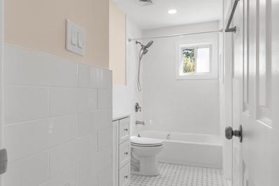 8 Hilltop Ave, West Babylon, NY 11704 - bathroom featuring tub / shower combination, toilet, a wainscoted wall, tile patterned floors, and tile walls