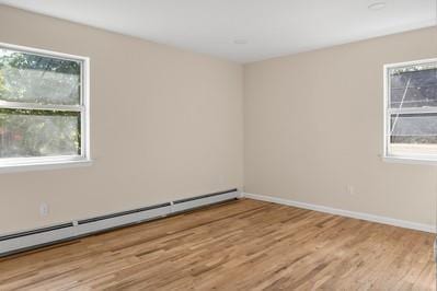 8 Hilltop Ave, West Babylon, NY 11704 - empty room featuring baseboard heating, light wood-style flooring, and baseboards