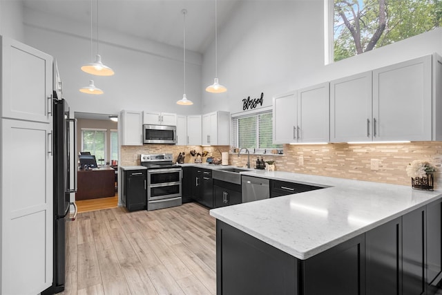 30 Apple Hill Dr, Cortlandt Manor, NY 10567 - kitchen featuring stainless steel appliances, high vaulted ceiling, a sink, a peninsula, and white cabinetry