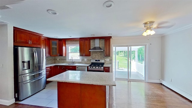 kitchen with appliances with stainless steel finishes, wall chimney exhaust hood, a baseboard radiator, a sink, and decorative backsplash