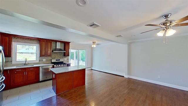 kitchen with stainless steel appliances, wall chimney range hood, a sink, ceiling fan, and a baseboard radiator
