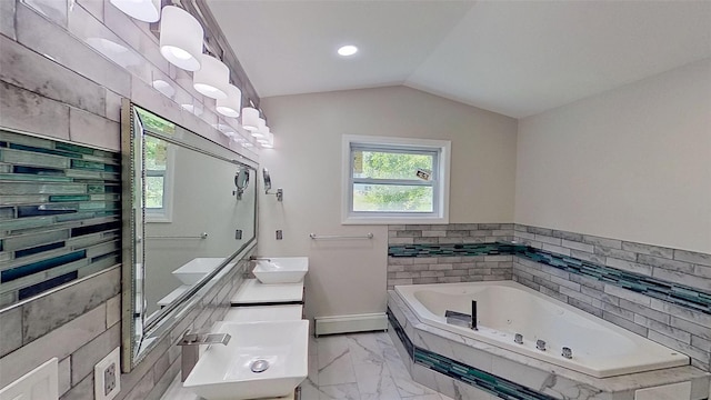 full bath with a sink, a jetted tub, marble look tiles, vaulted ceiling, and baseboards