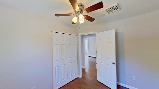 unfurnished bedroom featuring wood finished floors, a closet, baseboards, and a ceiling fan