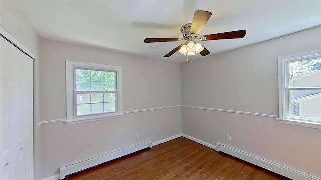 unfurnished bedroom featuring baseboard heating, wood finished floors, baseboards, and a closet