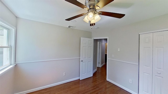 unfurnished bedroom featuring wood finished floors, a closet, baseboards, and ceiling fan