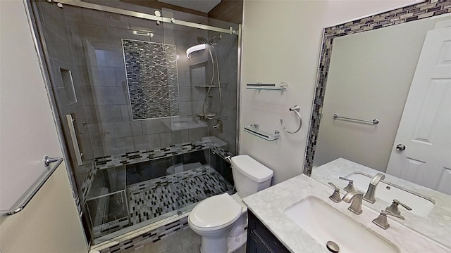 bathroom featuring toilet, a shower stall, and vanity