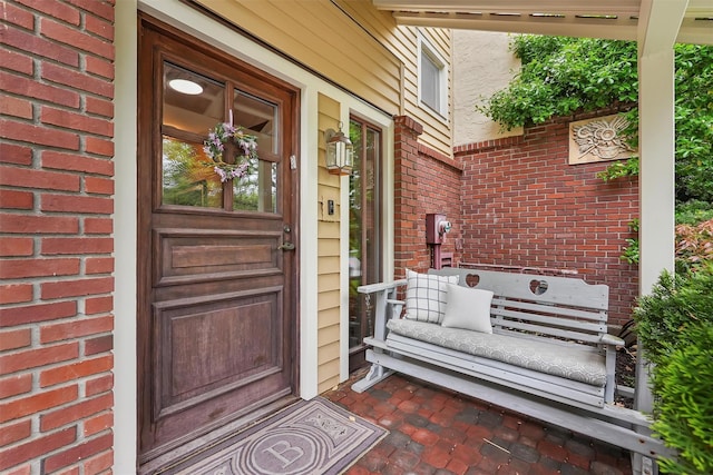 entrance to property featuring brick siding and covered porch