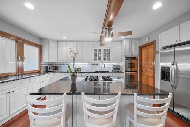 kitchen featuring stainless steel appliances, a sink, a center island, white cabinets, and recessed lighting