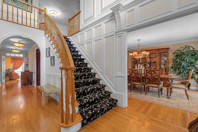 4 Point Cres, Malba, NY 11357 - stairs with arched walkways, wood finished floors, a chandelier, crown molding, and a decorative wall