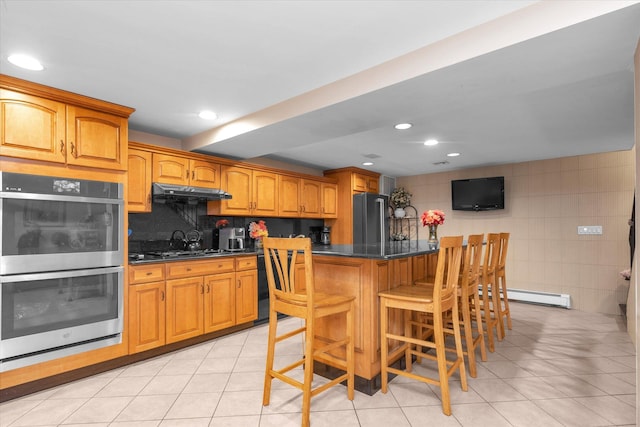 4 Point Cres, Malba, NY 11357 - kitchen with stainless steel appliances, baseboard heating, dark countertops, a kitchen island, and a kitchen bar