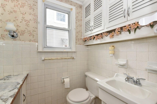 50 Fordham St, Williston Park, NY 11596 - bathroom with a sink, toilet, wallpapered walls, tile walls, and a wainscoted wall