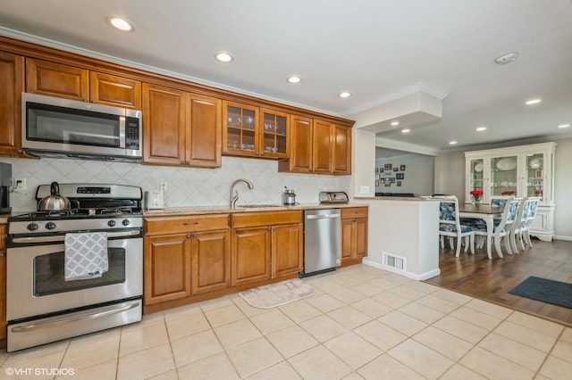 150 Arthur St, Massapequa Park, NY 11762 - kitchen with appliances with stainless steel finishes, a sink, brown cabinets, tasteful backsplash, and recessed lighting