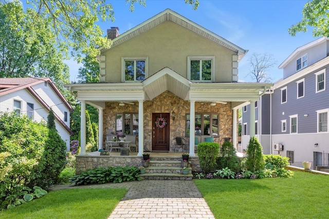 41-27 Orient Ave, Douglaston, NY 11363 - view of front facade featuring covered porch, stone siding, a front lawn, a chimney, and a ceiling fan