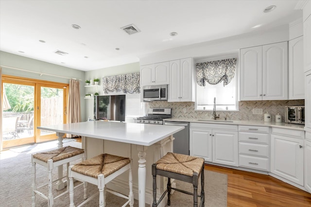 41-27 Orient Ave, Douglaston, NY 11363 - kitchen with stainless steel appliances, a sink, a breakfast bar, a kitchen island, and tasteful backsplash