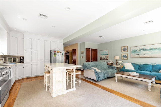 41-27 Orient Ave, Douglaston, NY 11363 - kitchen with open floor plan, light wood-type flooring, stainless steel appliances, and a breakfast bar area