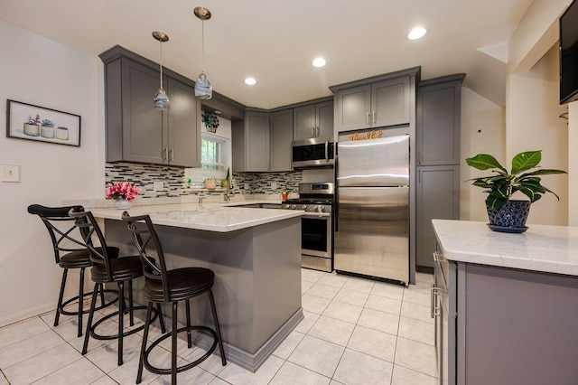 2588 Stedman Pl, Bronx, NY 10469 - kitchen featuring stainless steel appliances, a peninsula, decorative backsplash, a kitchen breakfast bar, and light stone countertops