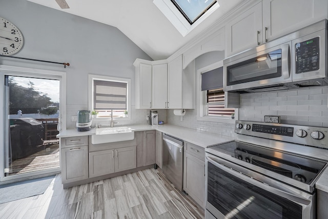 1203 Cross Bay Blvd, Broad Channel, NY 11693 - kitchen with appliances with stainless steel finishes, a skylight, vaulted ceiling, a sink, and light countertops