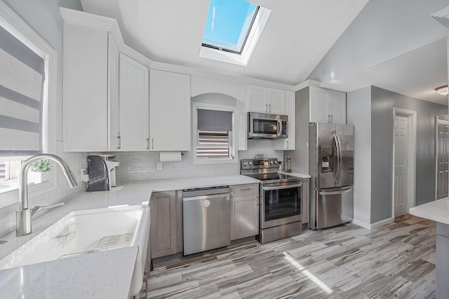 1203 Cross Bay Blvd, Broad Channel, NY 11693 - kitchen featuring stainless steel appliances, a sink, a skylight, decorative backsplash, and white cabinets