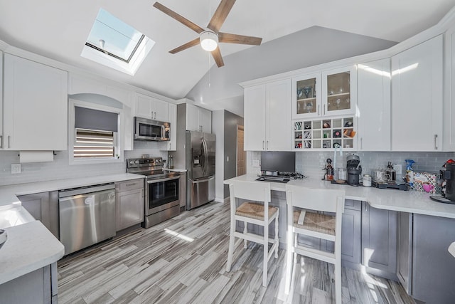 1203 Cross Bay Blvd, Broad Channel, NY 11693 - kitchen with appliances with stainless steel finishes, a skylight, ceiling fan, backsplash, and white cabinetry