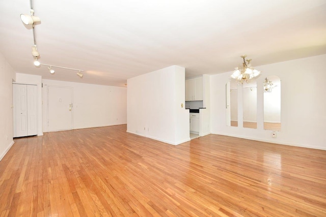 4 Birchwood Ct Unit 2K, Mineola, NY 11501 - unfurnished living room featuring a chandelier and light wood-style floors
