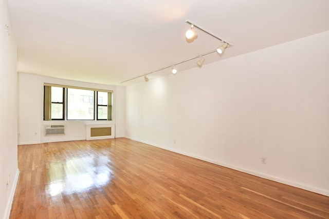 4 Birchwood Ct Unit 2K, Mineola, NY 11501 - spare room with a wall mounted air conditioner, rail lighting, light wood-type flooring, and baseboards