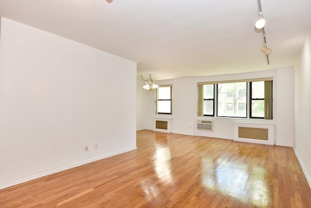 4 Birchwood Ct Unit 2K, Mineola, NY 11501 - empty room with a chandelier, light wood finished floors, track lighting, baseboards, and a wall mounted AC