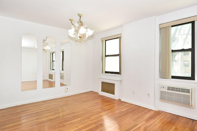 4 Birchwood Ct Unit 2K, Mineola, NY 11501 - unfurnished room with a chandelier, arched walkways, light wood-style floors, and plenty of natural light