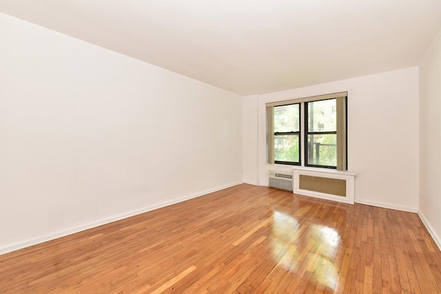 4 Birchwood Ct Unit 2K, Mineola, NY 11501 - empty room featuring light wood finished floors, baseboards, and a wall mounted air conditioner