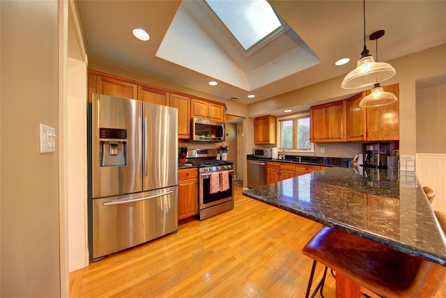 55 Richfield St, Plainview, NY 11803 - kitchen with stainless steel appliances, brown cabinetry, light wood-style flooring, a peninsula, and a skylight