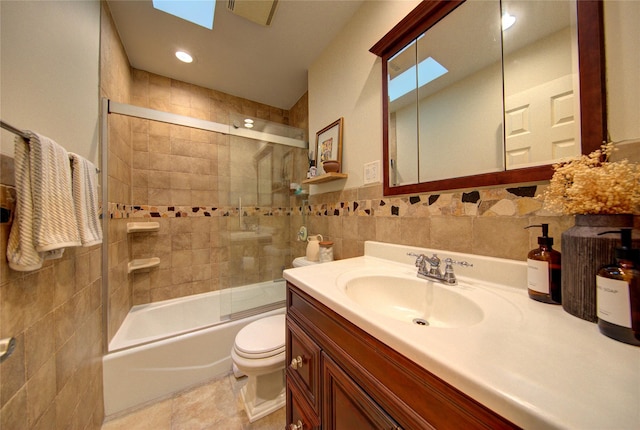55 Richfield St, Plainview, NY 11803 - bathroom with tile walls, toilet, vanity, combined bath / shower with glass door, and a skylight