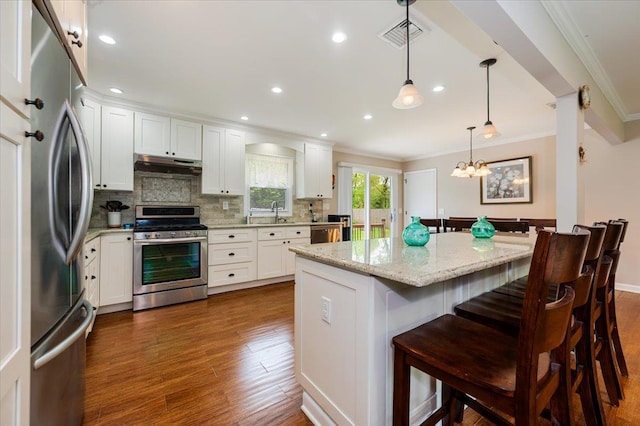 4200 Rocky Point Rd, East Marion, NY 11939 - kitchen featuring stainless steel appliances, ornamental molding, under cabinet range hood, dark wood-style floors, and tasteful backsplash