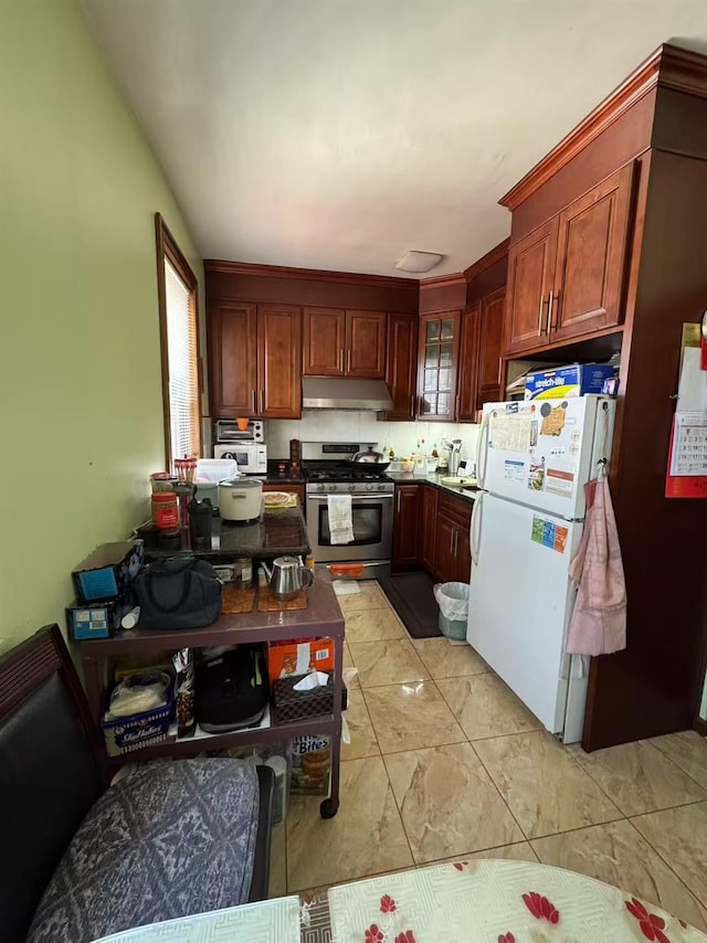 59-32 163rd St, Fresh Meadows, NY 11365 - kitchen featuring stainless steel gas range oven, freestanding refrigerator, under cabinet range hood, glass insert cabinets, and light marble finish floors