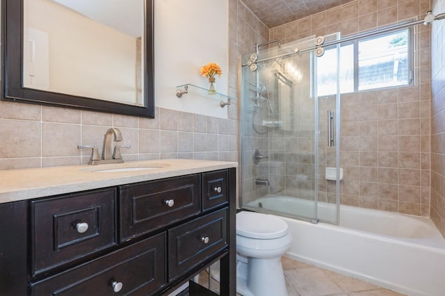 2033 Waltoffer Ave, North Bellmore, NY 11710 - full bath featuring tile walls, toilet, tile patterned floors, vanity, and bath / shower combo with glass door