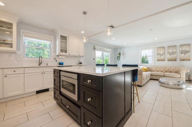 2033 Waltoffer Ave, North Bellmore, NY 11710 - kitchen with crown molding, stainless steel microwave, light countertops, plenty of natural light, and recessed lighting