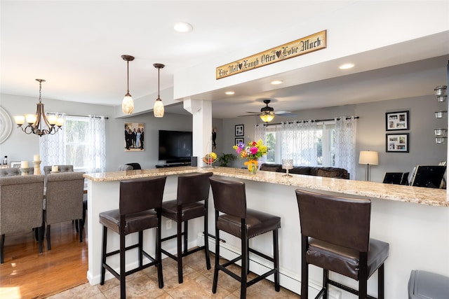 17 Daytona Beach Pl, Coram, NY 11727 - kitchen featuring open floor plan, a breakfast bar area, light stone countertops, recessed lighting, and decorative light fixtures