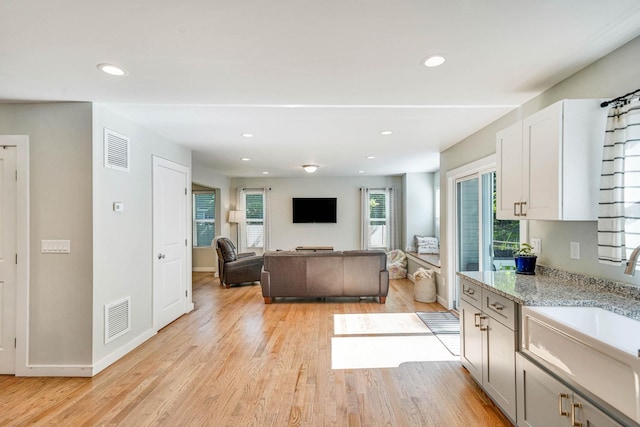 59 Middle Island Blvd, Middle Island, NY 11953 - kitchen featuring light wood-style floors, baseboards, light stone counters, recessed lighting, and a sink