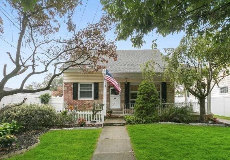 2482 Soper Ave, Baldwin, NY 11510 - bungalow featuring covered porch, brick siding, and roof with shingles