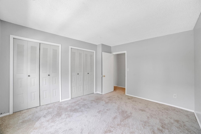 32 Huntington Cir Building 19, Peekskill, NY 10566 - unfurnished bedroom featuring two closets, a textured ceiling, carpet, and baseboards