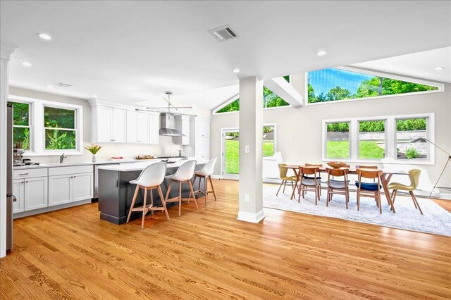 530 N Midland Ave N, Nyack, NY 10960 - kitchen with wall chimney exhaust hood, white cabinets, light wood-style flooring, light countertops, and vaulted ceiling