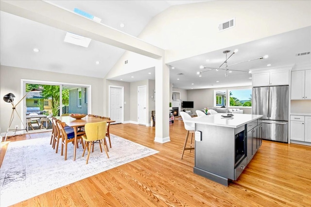 530 N Midland Ave N, Nyack, NY 10960 - kitchen with stainless steel fridge, vaulted ceiling, light wood-type flooring, white cabinets, and light countertops