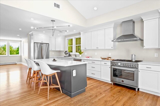 530 N Midland Ave N, Nyack, NY 10960 - kitchen with wall chimney range hood, stainless steel appliances, light wood-style flooring, a breakfast bar, and recessed lighting