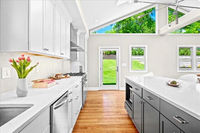 530 N Midland Ave N, Nyack, NY 10960 - kitchen featuring appliances with stainless steel finishes, white cabinetry, wall chimney range hood, light wood-style floors, and a sink