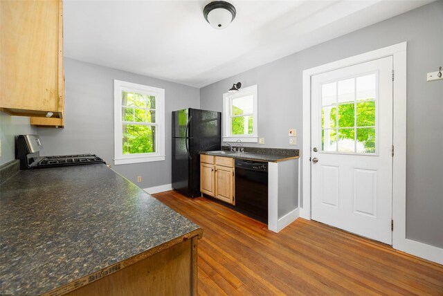 kitchen featuring black appliances, dark countertops, dark wood-style floors, a sink, and baseboards